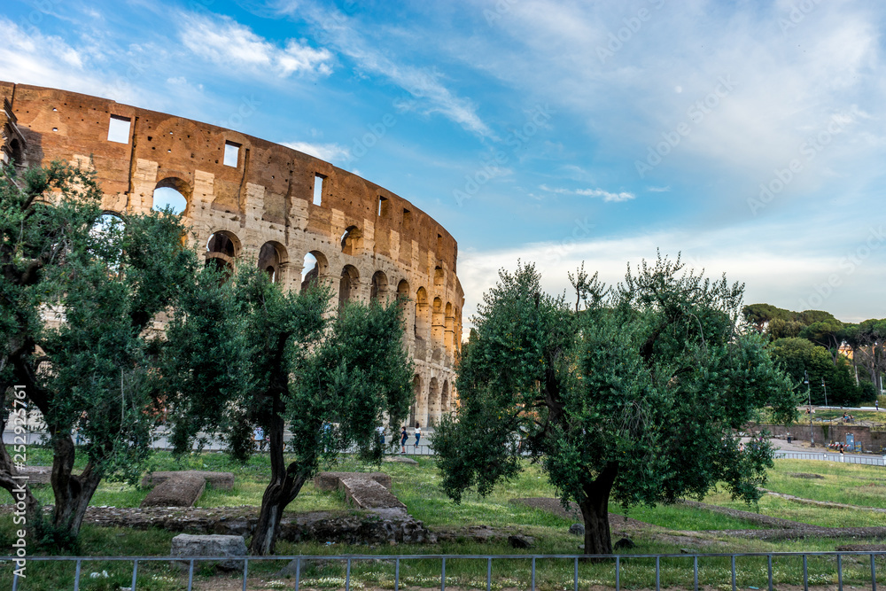 Fototapeta premium Golden sunset at the Great Roman Colosseum (Coliseum, Colosseo), also known as the Flavian Amphitheatre. Famous world landmark. Scenic urban landscape.