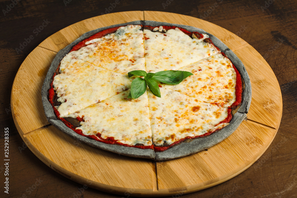Cheese Pizza, black pastry on a wooden board. Decorated with greens. Cheese Pizza, black pastry on a wooden board. Decorated with greens.