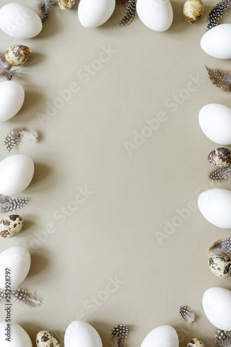 Easter background. Easter frame made of white eggs, quail eggs and feathers with copy space.