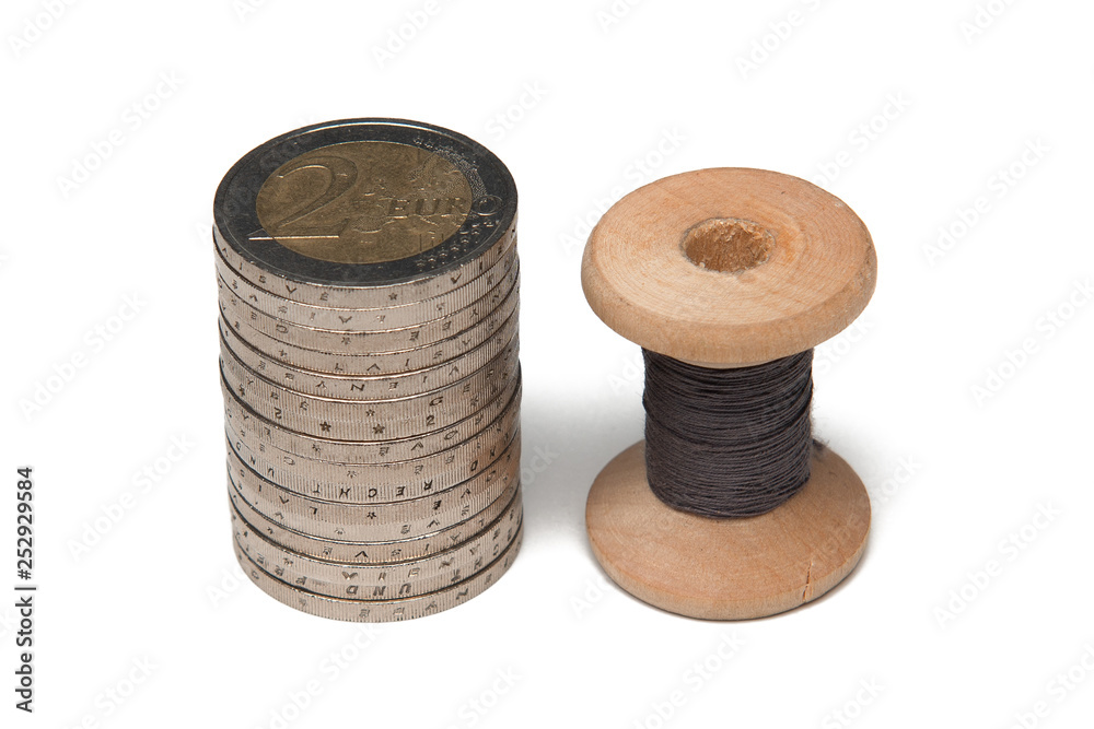 Rows of coins isolated on white background next to multicolored thread on wooden spool Rows of coins isolated on white background next to multicolored thread on wooden spool