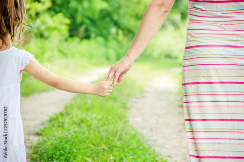 Mom and daughter are walking along the road holding hands. photo