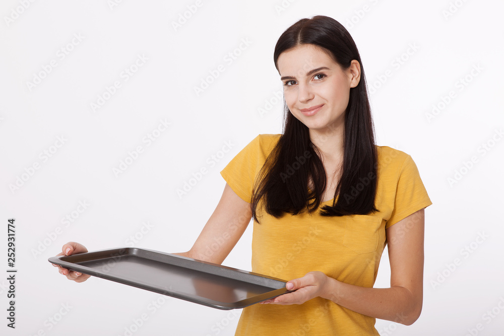 Young attractive woman holding an empty tray isolated on white background. Woman in yellow T-shirt friendly smiles. Blank template for design of the tray. Young attractive woman holding an empty tray isolated on white background. Woman in yellow T-shirt friendly smiles. Blank template for design of the tray.