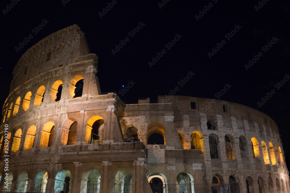 Naklejka premium Night at the Great Roman Colosseum (Coliseum, Colosseo), also known as the Flavian Amphitheatre with lights & illumination.