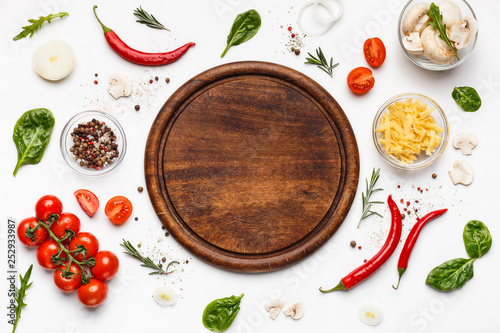 Round cutting board with pizza ingridients around photo