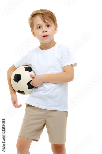 A little boy wearing a pure white t-shirt is playing with a socc