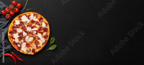 Pepperoni pizza on black background, top view