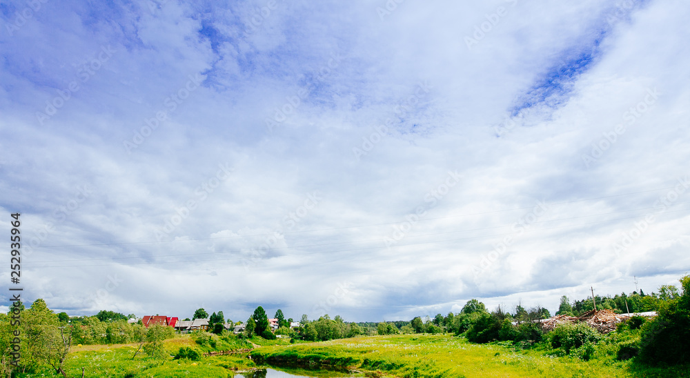 Fototapeta premium Spring summer background - rural road in green grass field meadow scenery lanscape with blue sky