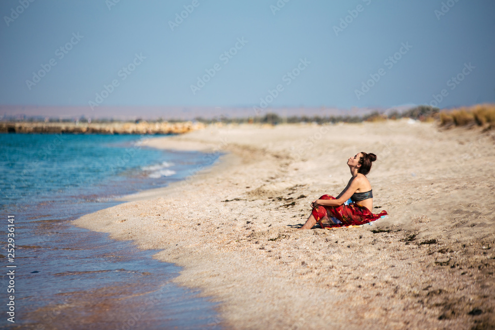 pretty girl dressed in red skirt relaxing on the beach, sea cost