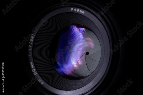 Lens aperture low light photo closeup. Colorful light traces on glass. Aperture blades is clean and dark. Stock photo isolated on black background.