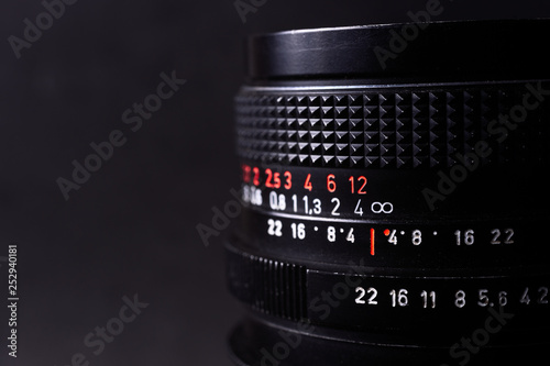 Vintage lens scales symbols closeup. Stock photo with blurred gray background. Aperture symbols and focusing distance signs on lens.