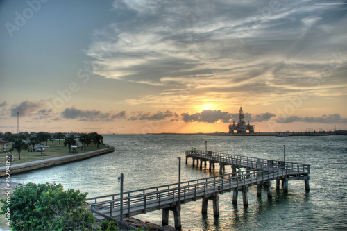 Oil rig in construction in bay with setting sun behind it