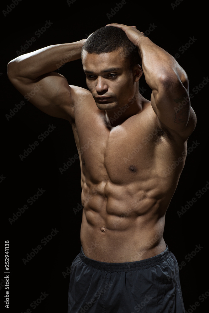 Perfect body. Vertical shot of an African man with toned body posing shirtless in studio Perfect body. Vertical shot of an African man with toned body posing shirtless in studio