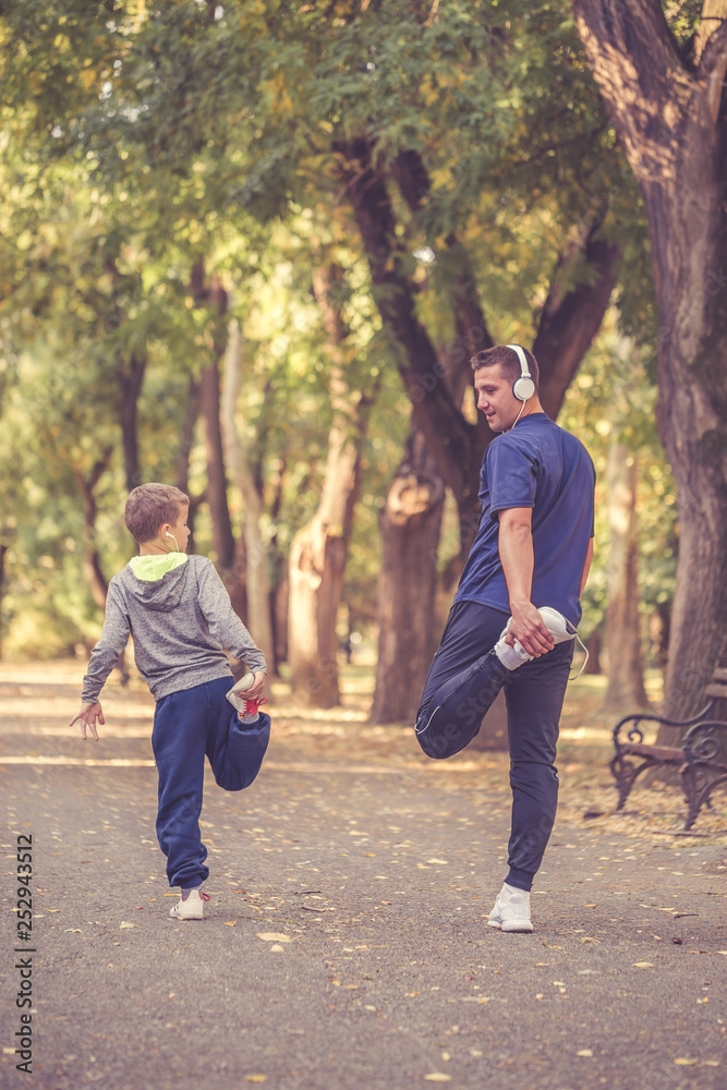 Little boy and his father stretching leg together in the park