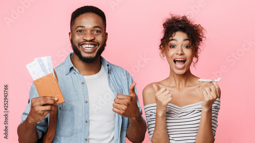 African-american couple holding flying tickets and showing thumbs up