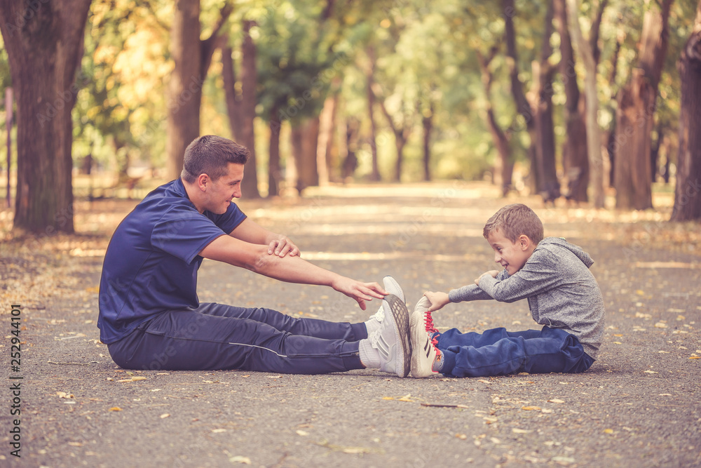Father and his little son exercising together outdoors Father and his little son exercising together outdoors