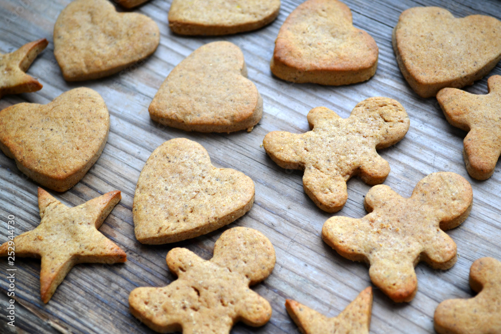 Gingerbread cookies in shapes of heart, star and man with cinnamon stick and ginger root on wooden table Gingerbread cookies in shapes of heart, star and man with cinnamon stick and ginger root on wooden table