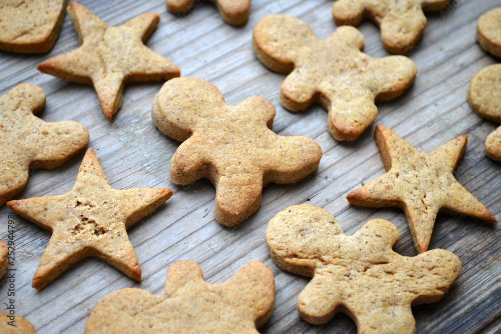 Gingerbread cookies in shapes of heart, star and man with cinnamon stick and ginger root on wooden table Gingerbread cookies in shapes of heart, star and man with cinnamon stick and ginger root on wooden table