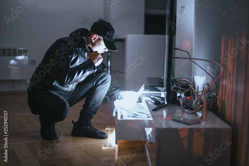 Thief with torch stealing valuable things, long exposure motion blur