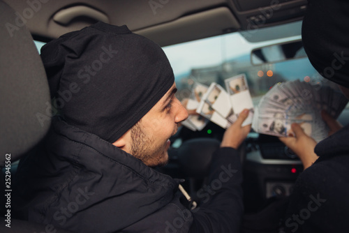 Two happy bank robbers celebrating their successful hit while sitting in the car they used for the robbery.