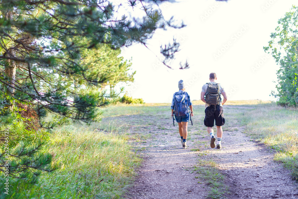 Young couple walking in the forest. Hiking concept in the mountain in summer Young couple walking in the forest. Hiking concept in the mountain in summer