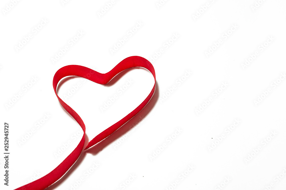 Heart made of red ribbon. Placed on white paper background. Heart made of red ribbon. Placed on white paper background.