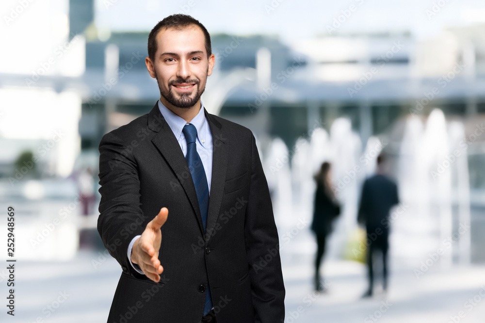 Handsome businessman offering handshake in an urban setting Handsome businessman offering handshake in an urban setting