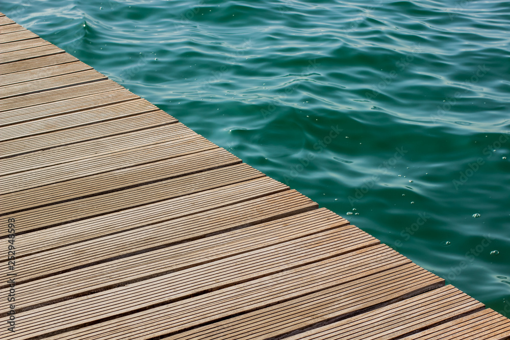 simple background pattern concept photography of wooden deck floor edge and green blue water surface of swimming pool, copy space