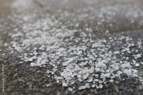 De-icing chemicals on the pavement. Pavement is sprinkled with technical salt or salt mixtures based on it, soft focus, copy space. Reagent - technical salt will make the road safe.  photo