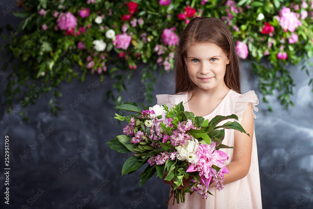 Portrait of the lovely little girl with a bouquet of flowers. Looking at camera. Copy space