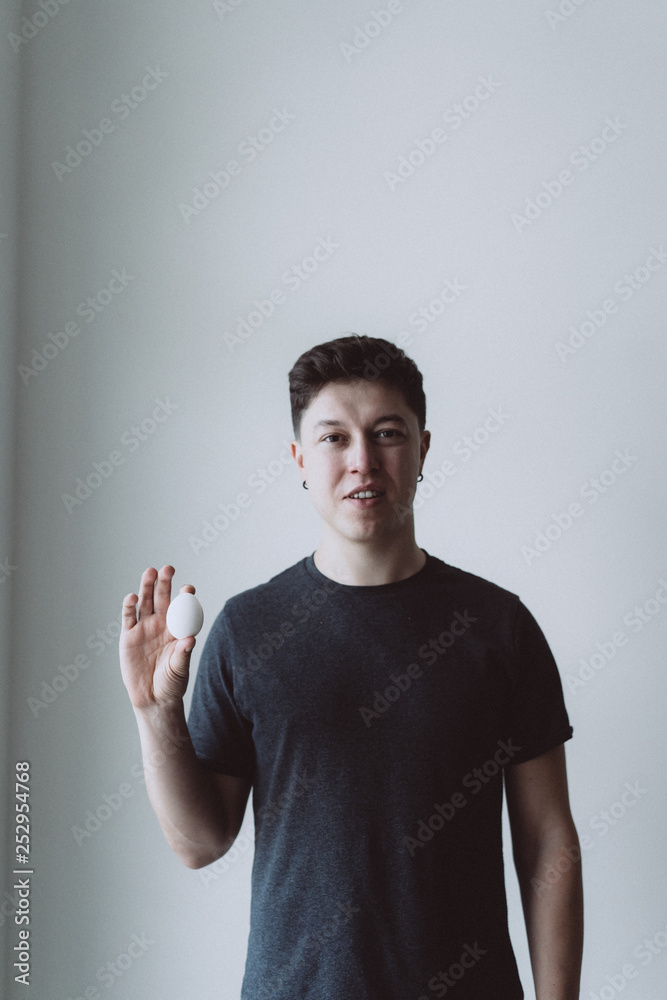 handsome man holding egg on gray background handsome man holding egg on gray background