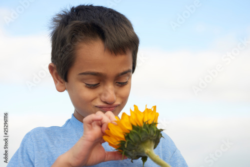 portrait of child outdoors smelling a sunflower