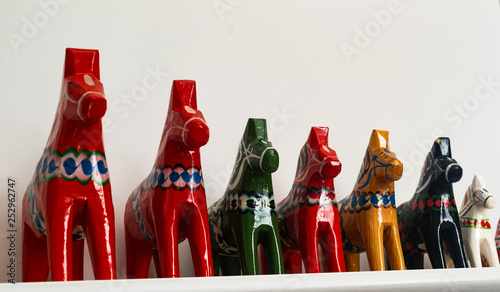 Colorful handmade Swedish Dala Horses lined up on a shelf photo