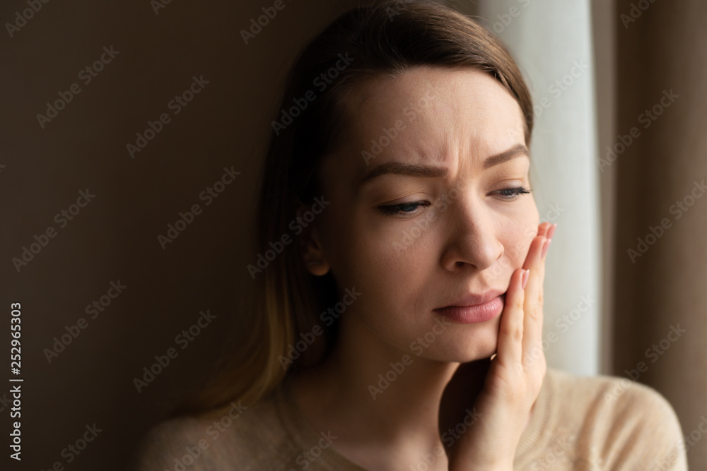 Toothache and dentistry. A beautiful young woman suffers from terrible severe pain in her teeth, touching her cheek with her hand. Dental care and health concept, dark background with space. Toothache and dentistry. A beautiful young woman suffers from terrible severe pain in her teeth, touching her cheek with her hand. Dental care and health concept, dark background with space.
