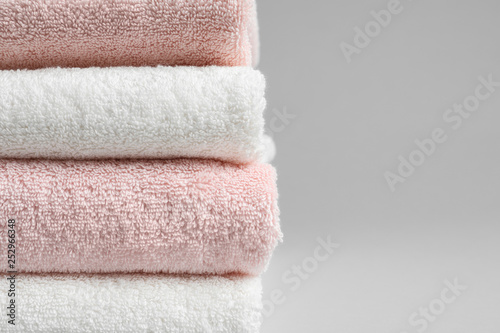 Stack of fresh towels on grey background, closeup. Space for text
