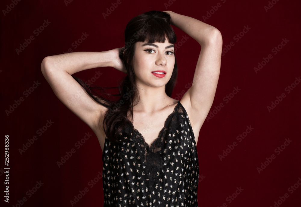 Beautiful Young Girl Pushing Long Dark Hair Back in a Floral Print Slip Dress Against a Dark Red Backdrop Beautiful Young Girl Pushing Long Dark Hair Back in a Floral Print Slip Dress Against a Dark Red Backdrop