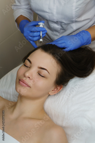 Aesthetic cosmetology. Facelift in spa salon. Beautician makes injections in the forehead. Smoothing of mimic wrinkles.