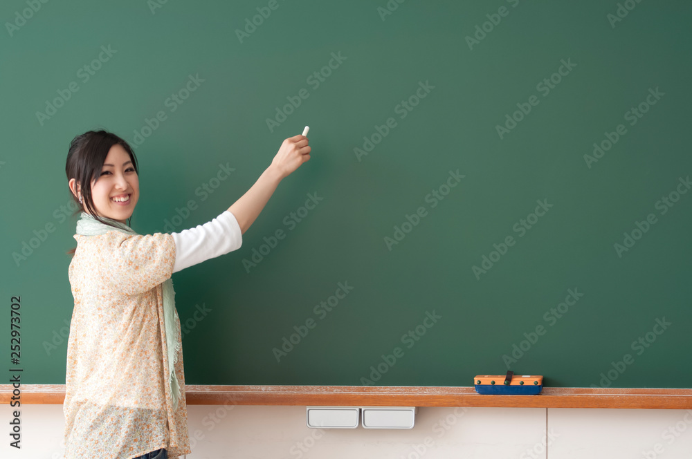 黒板に文字を書こうとする大学生 黒板に文字を書こうとする大学生