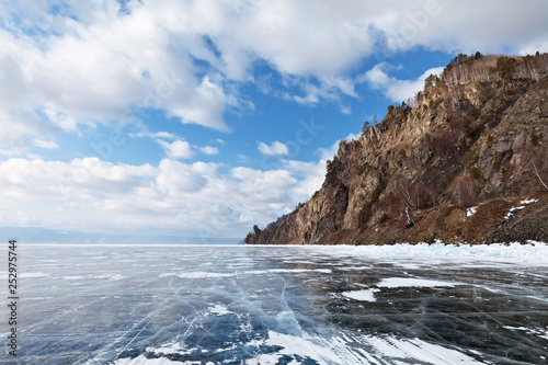 Lake Baikal. Winter road on the ice of the lake along the Circum-Baikal Railway. The Cape Stolby is visible in the distance. Traveling by car on the ice of frozen lake