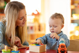 Kid playing logical toys with educator or mother in the classroom in nursery or preschool