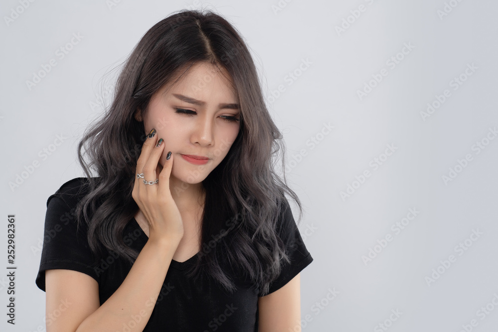 Asian woman holds for face feeling painful toothache. Dental care and health concept. Beautiful young female suffering from toothache on grey background. Asian woman holds for face feeling painful toothache. Dental care and health concept. Beautiful young female suffering from toothache on grey background.