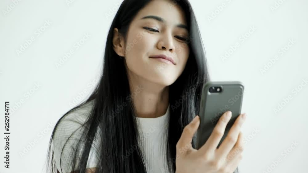 Young beautiful asian woman using mobile phone to video call with her friends, happy mood. Millennial lifestyle concept. Young beautiful asian woman using mobile phone to video call with her friends, happy mood. Millennial lifestyle concept.