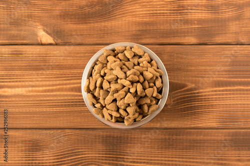 Bowl with dog food on a wooden table. Close up.