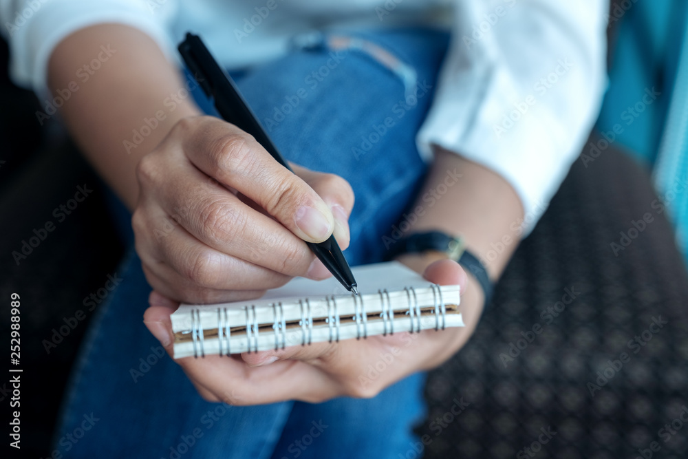 Closeup image of a woman's hands holding and writing on blank notebook Closeup image of a woman's hands holding and writing on blank notebook