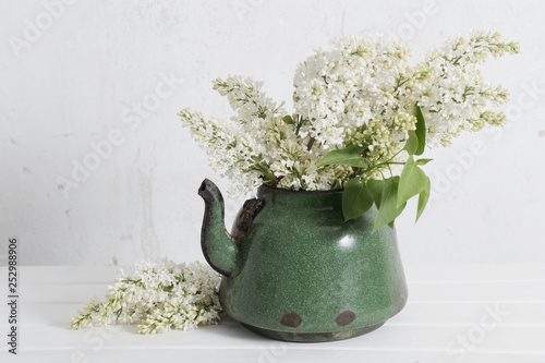 white lilac in old teapot on white background