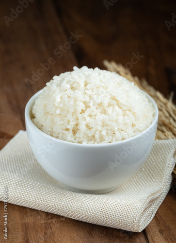 Steam White rice in white ceramic bowl on wood table for healthy meal.