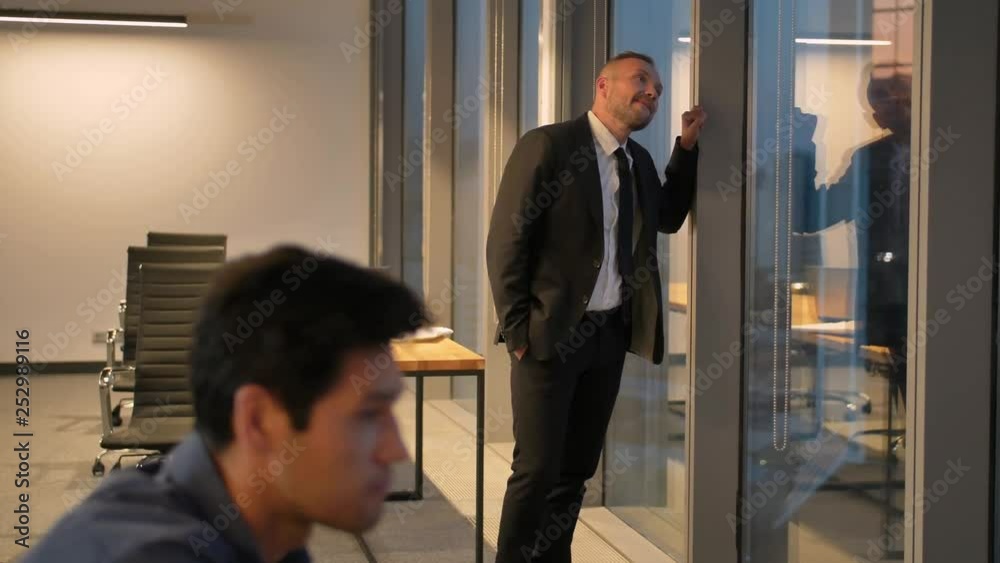 Front view of successful businessman in suit standing in office with hands in pockets. Front view of successful businessman in suit standing in office with hands in pockets.