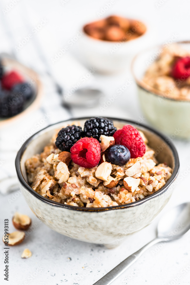 Oatmeal porridge with berries, seeds and nuts in bowl. Healthy breakfast, vegan or vegetarian diet, weight loss, paleo food concept Oatmeal porridge with berries, seeds and nuts in bowl. Healthy breakfast, vegan or vegetarian diet, weight loss, paleo food concept