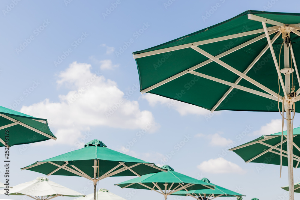 Sun green open umbrella, comfortable rest by the ocean with personal beach parasol on beautiful cote dazur coastline, safe tan accessory, sunstroke protection.Summer concept, vacation