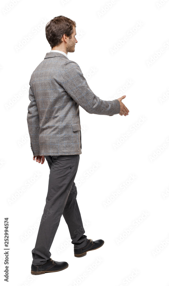 Back view of a walking businessman who stretches his hand for a handshake.