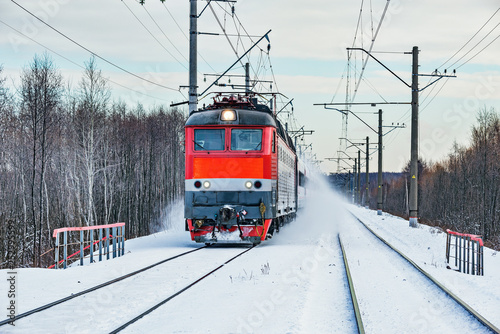 Passenger train approaches to the station at winter morning time.